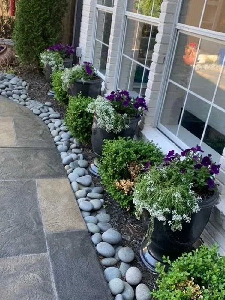 A hardscaped walkway adorned with potted plants and rocks in North Dallas and surrounding areas offers stunning landscape design.