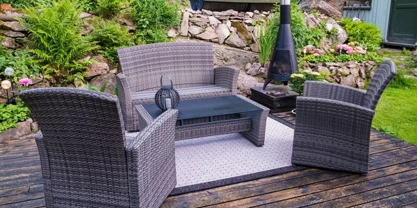 A wicker patio furniture set in a landscaped outdoor space.